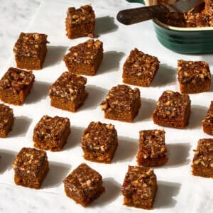 Sweet Potato Blondie with Pecan Pie Bites in 4 rows of 5 with a casserole pan and spatula at the top of the left hand corner.